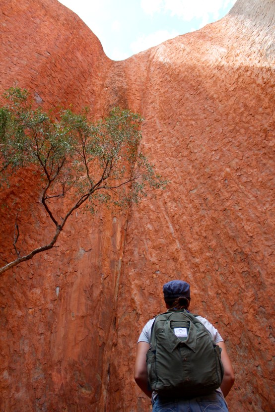 Looking up at Uluru rock face backpack Northern Territory